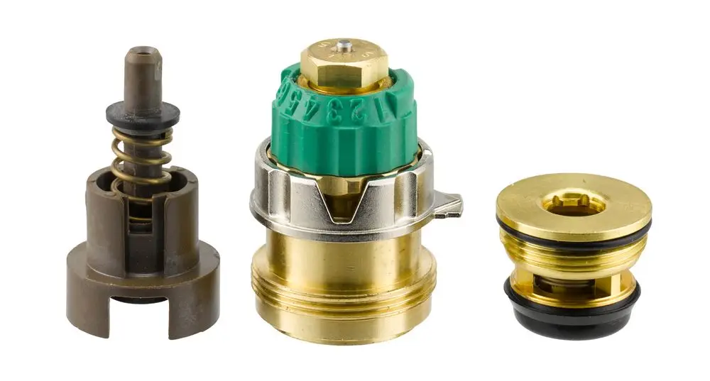 Drei Komponenten einer Innengarnitur für Ventile, darunter eine Druckregelungseinheit, dargestellt in Metall mit einer grünen Kappe, produziert von Danfoss.